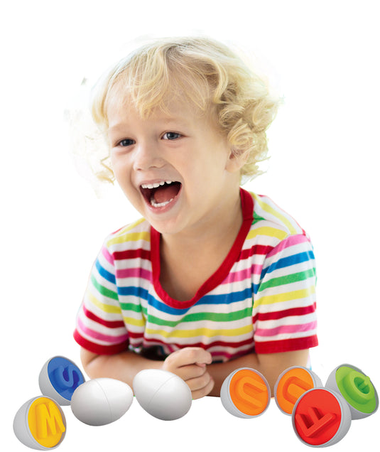 Child laughing while playing with Alphabet Eggs, holding egg halves with embossed letters